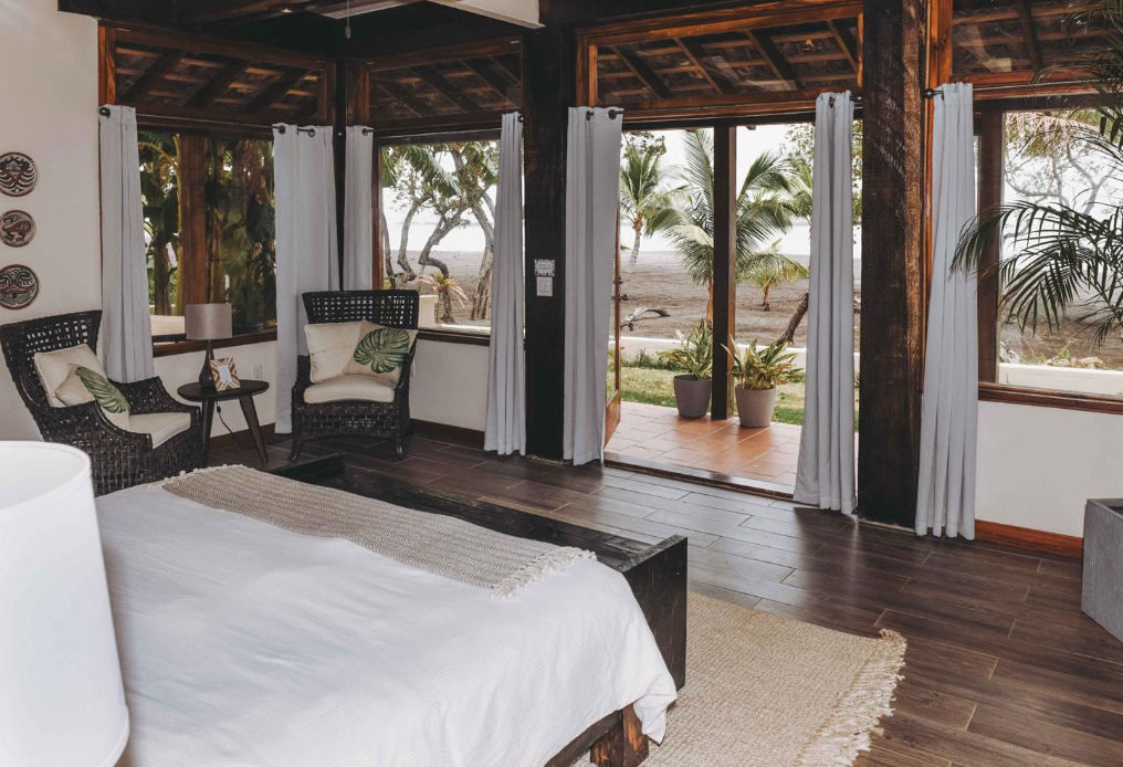 A bedroom with a bed , chairs , and a sliding glass door.