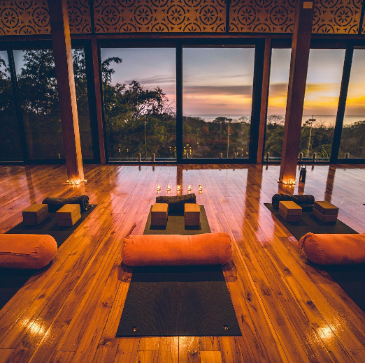 A room with a lot of windows and yoga mats on the floor.