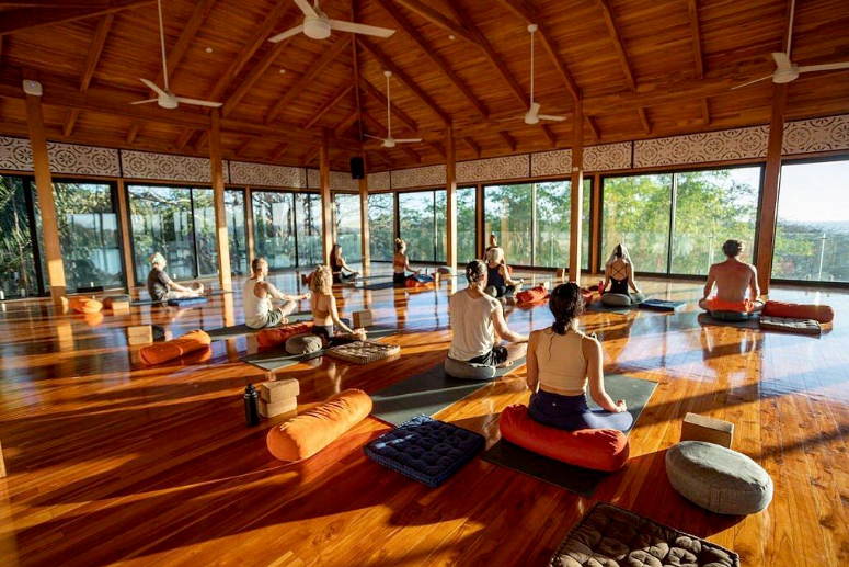 A group of people are doing yoga in a large room.