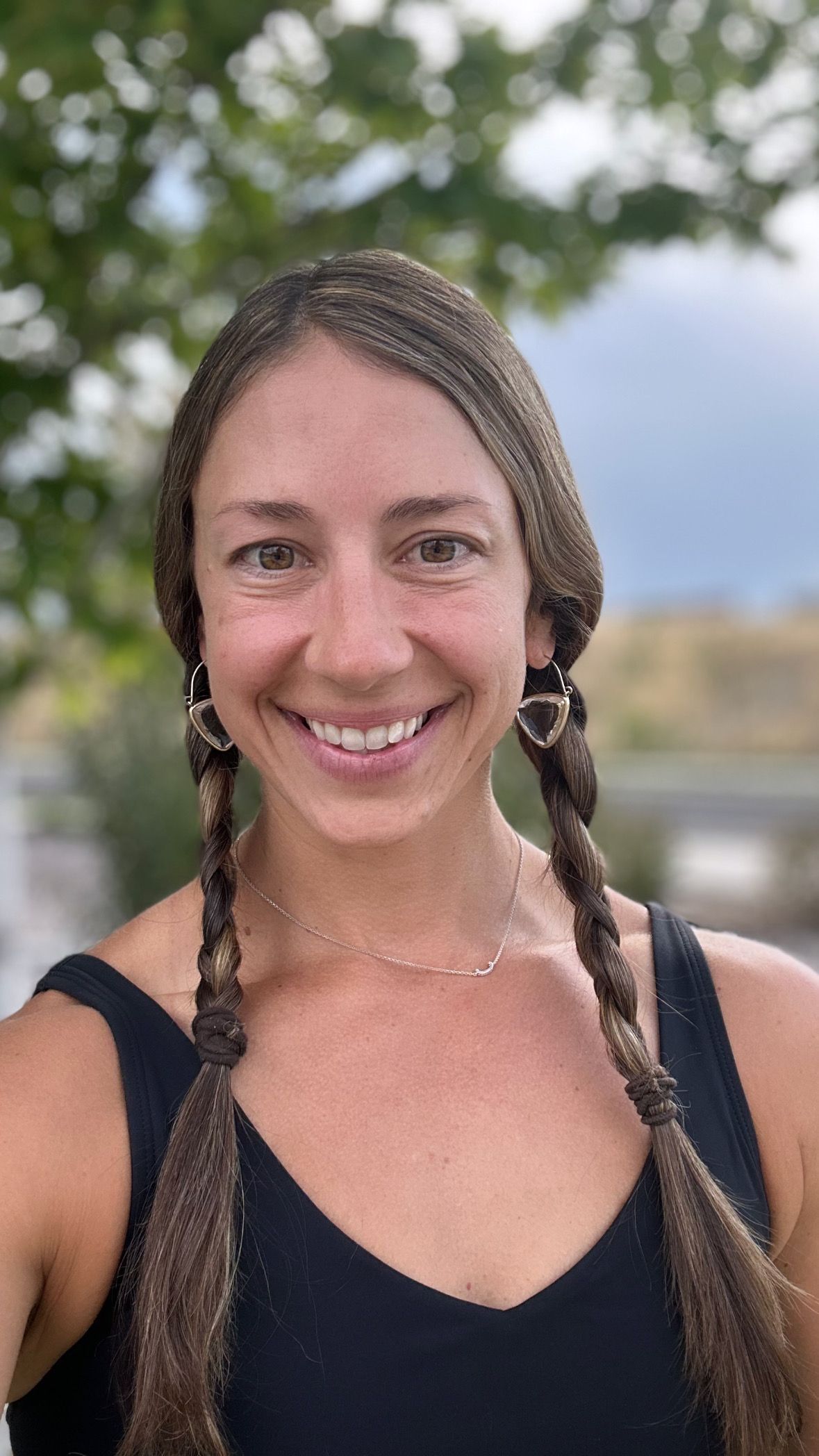A woman with braids and earrings is smiling for the camera.
