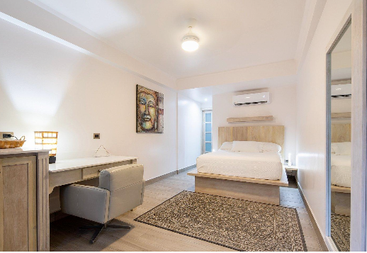 A bedroom with a bed , chair , desk and mirror.