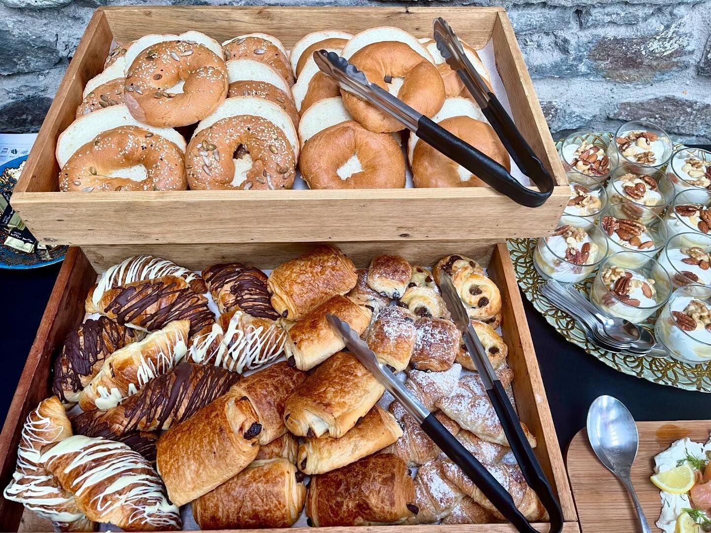 A wooden tray filled with a variety of pastries and donuts.