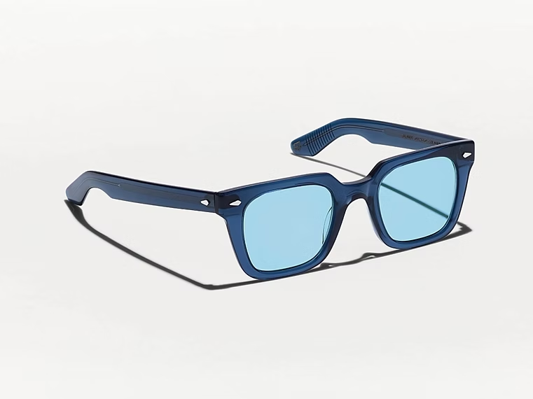 Occhiali da sole con montatura blu e lenti azzurre su sfondo bianco.