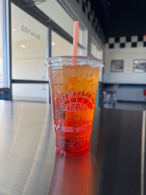 A cup of iced tea with a straw on a table.