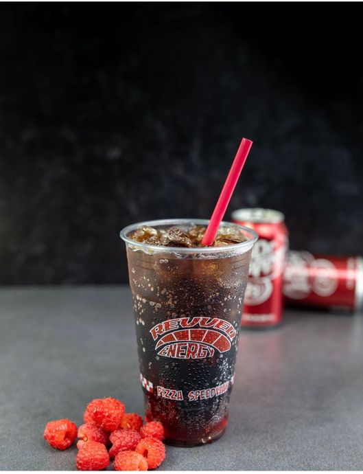 A cup of soda with a red straw and raspberries next to it.