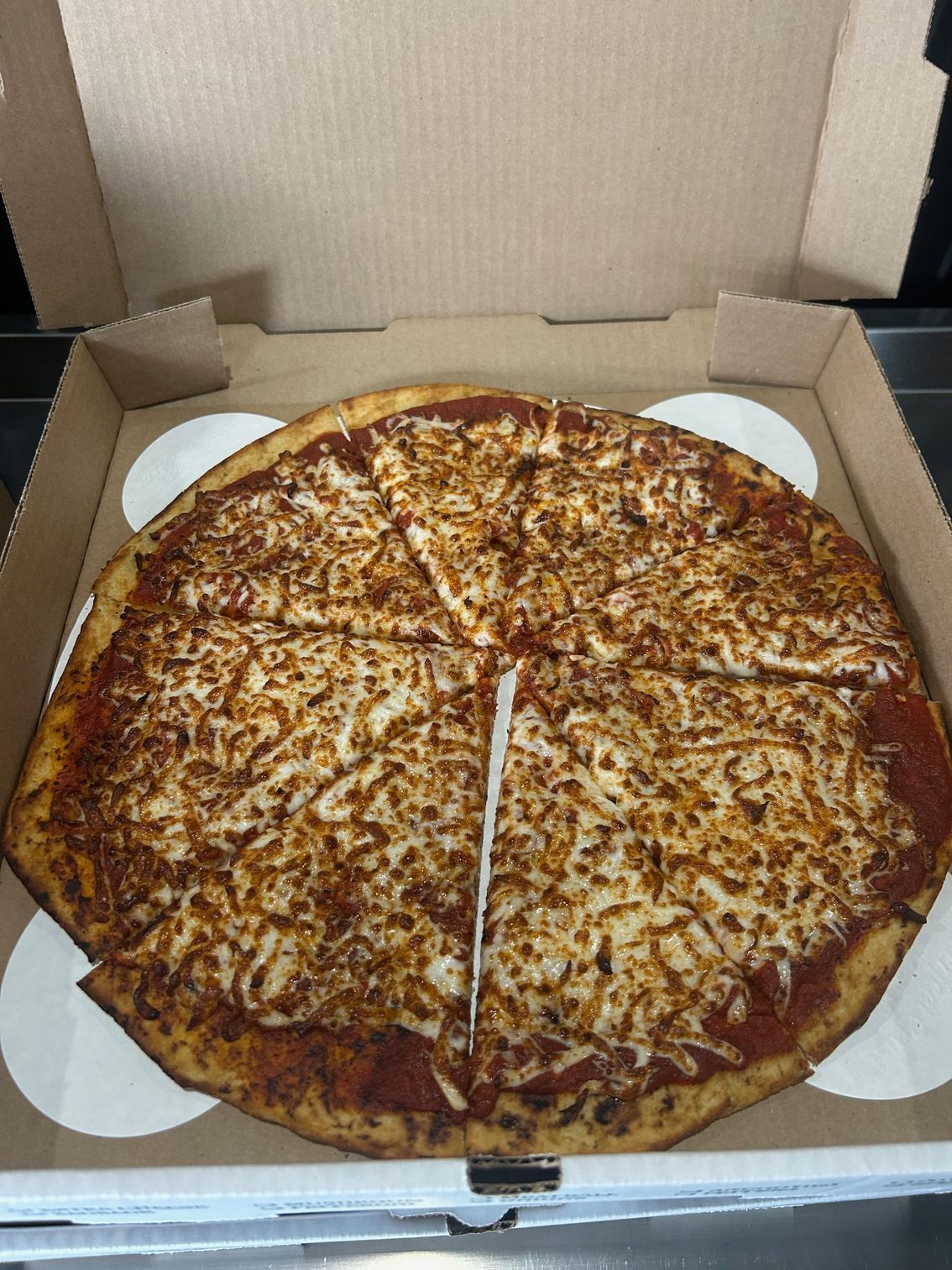 A pizza is sitting in a cardboard box with a slice missing.