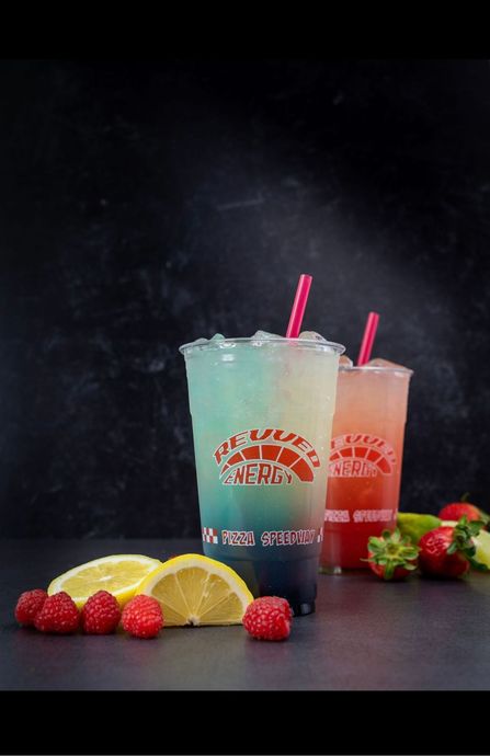 Two drinks with straws and raspberries on a table.