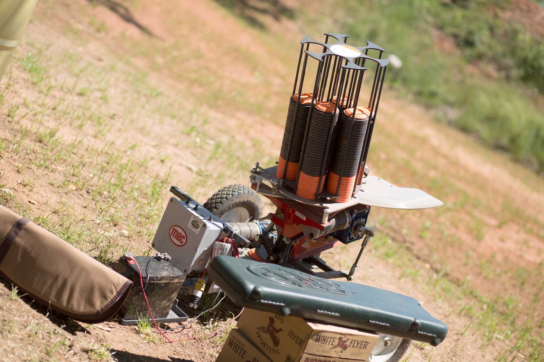 A bunch of shotguns are sitting on top of a table in the grass.