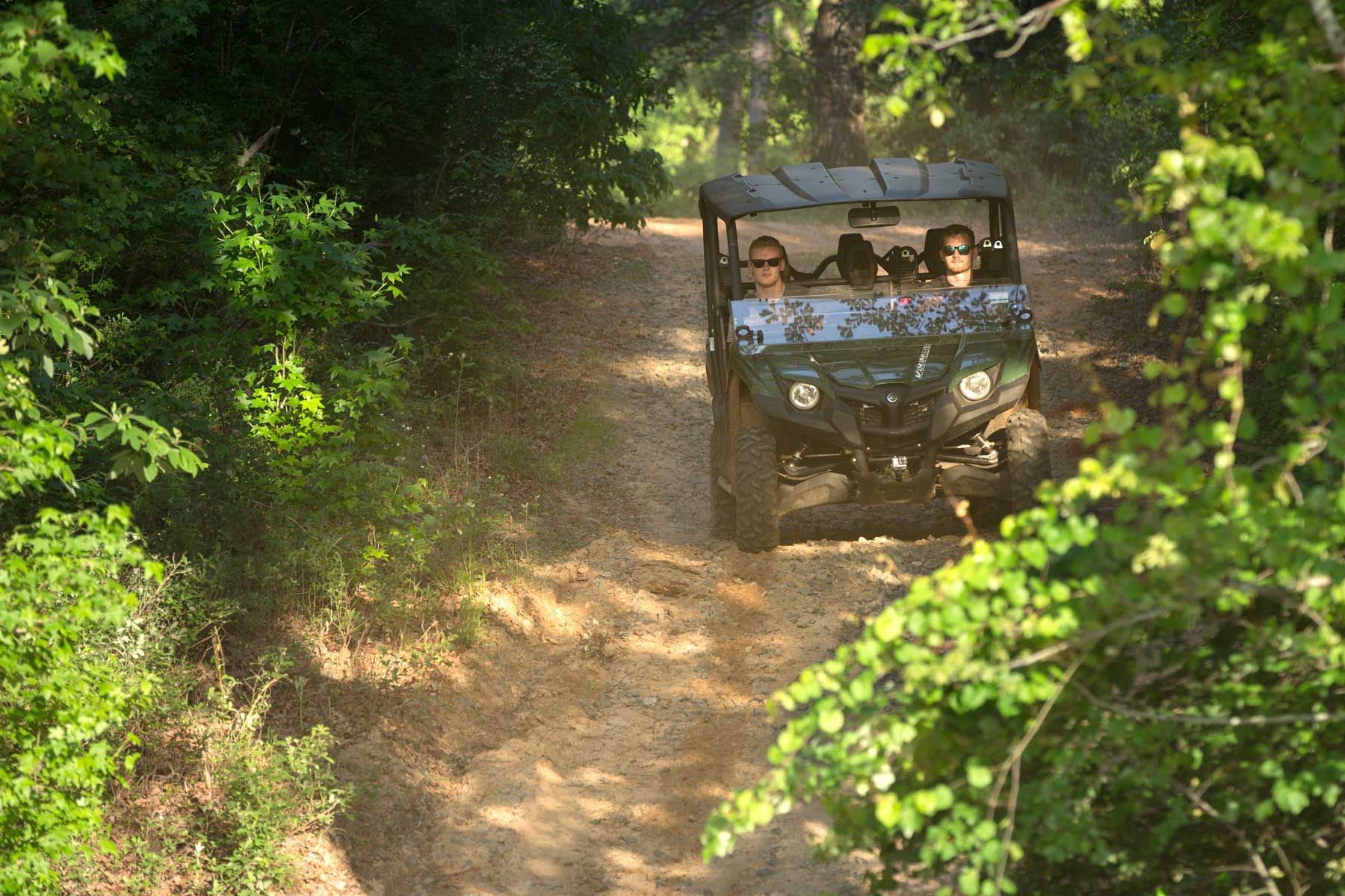 A group of people are riding a atv down a dirt road.