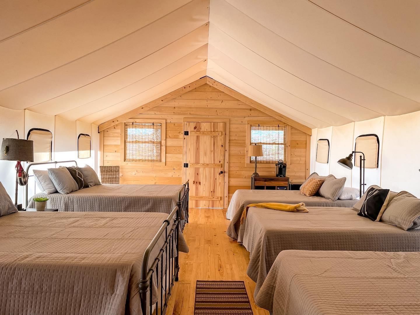 A room with four beds in it and a wooden ceiling.