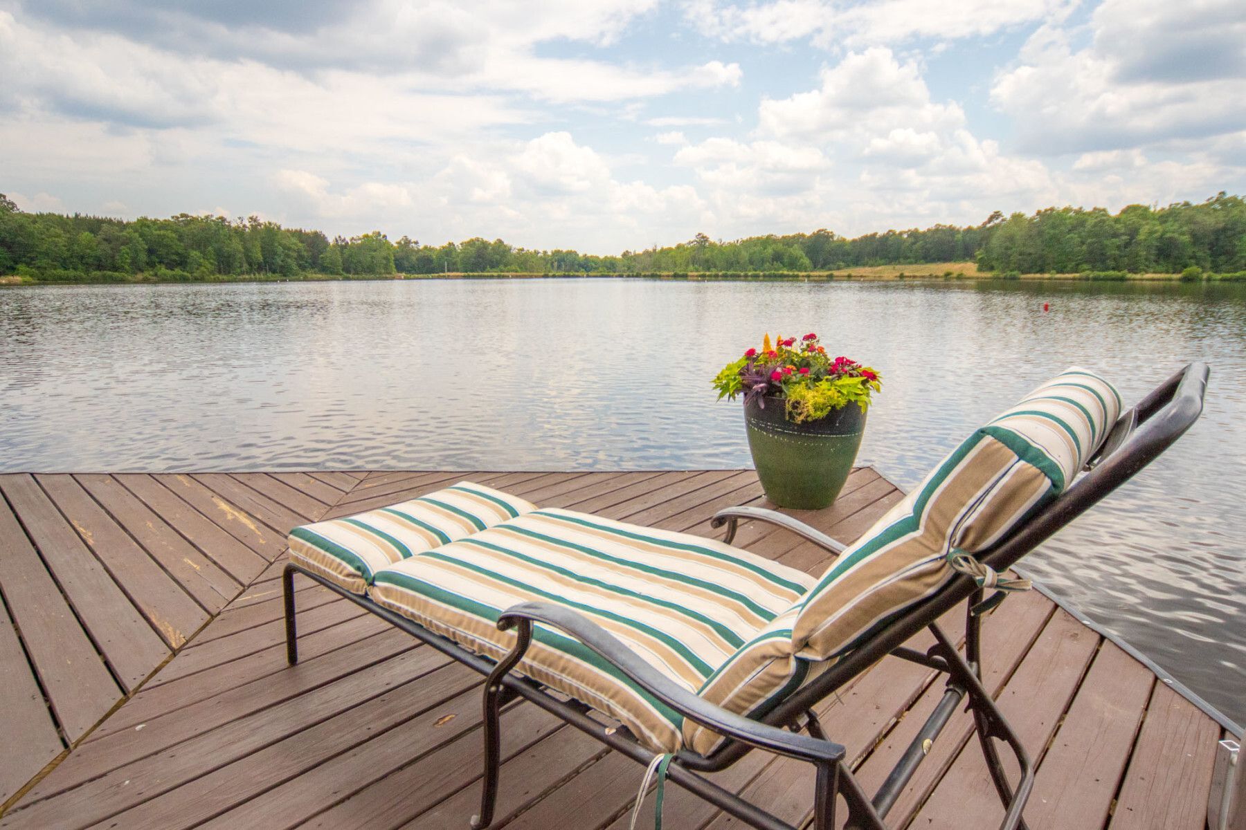 A lounge chair is sitting on a dock overlooking a lake.