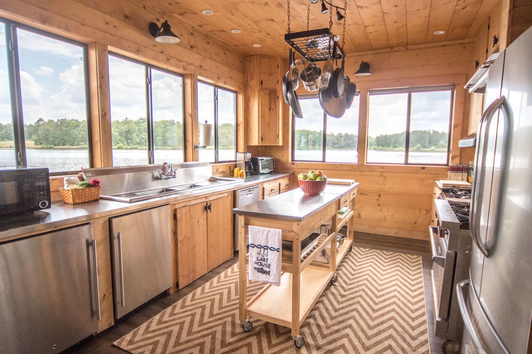 A kitchen with stainless steel appliances , wooden cabinets , and a large island.