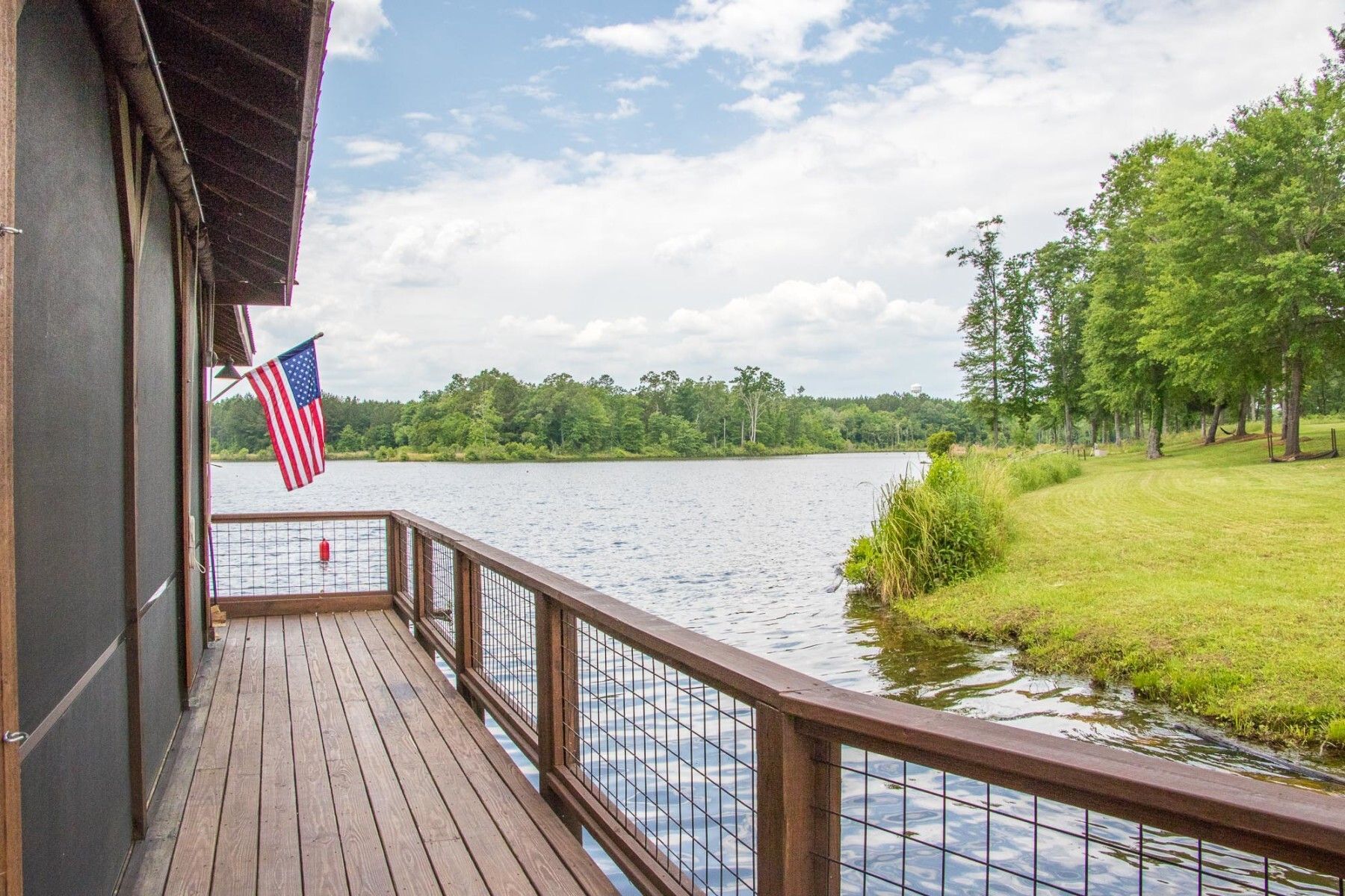 A deck overlooking a lake with an american flag hanging from it.