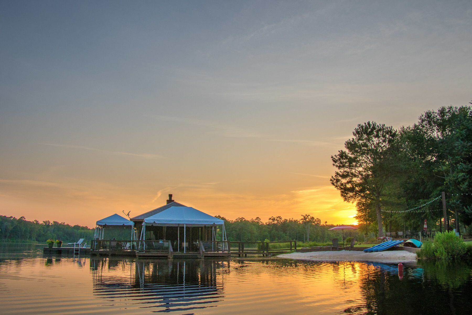 A house on a dock in the middle of a lake at sunset.