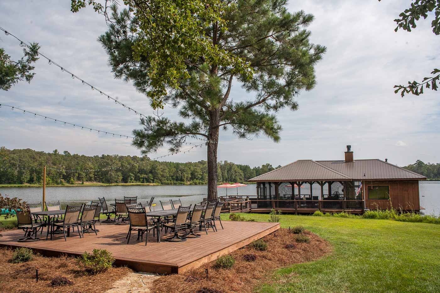 A wooden deck with tables and chairs next to a lake.