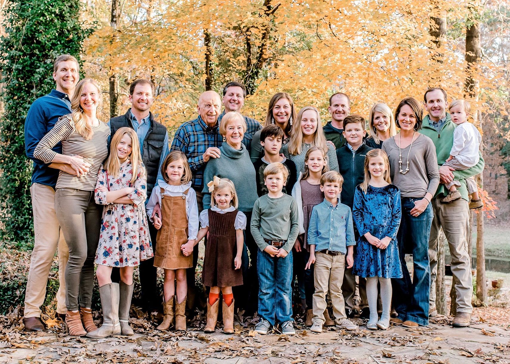 A large family is posing for a picture in the woods.