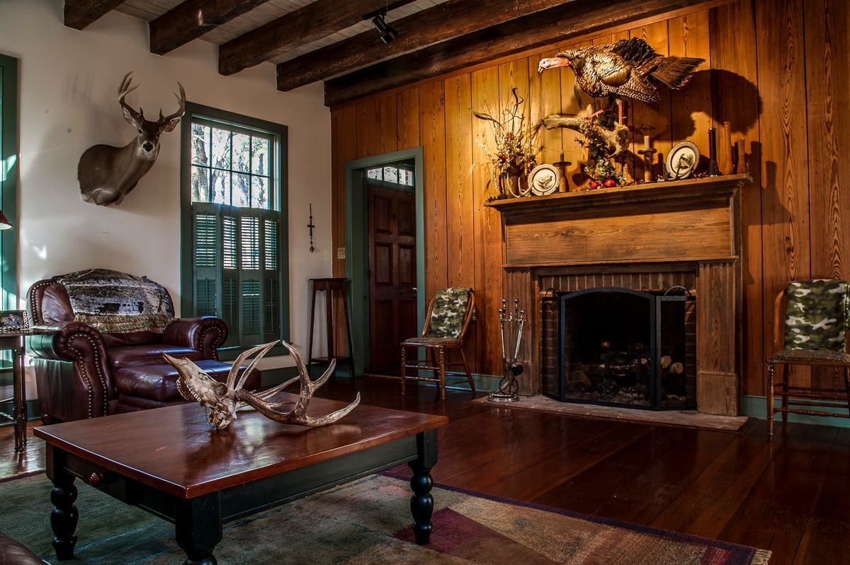 A living room with a fireplace and a deer head on the wall.