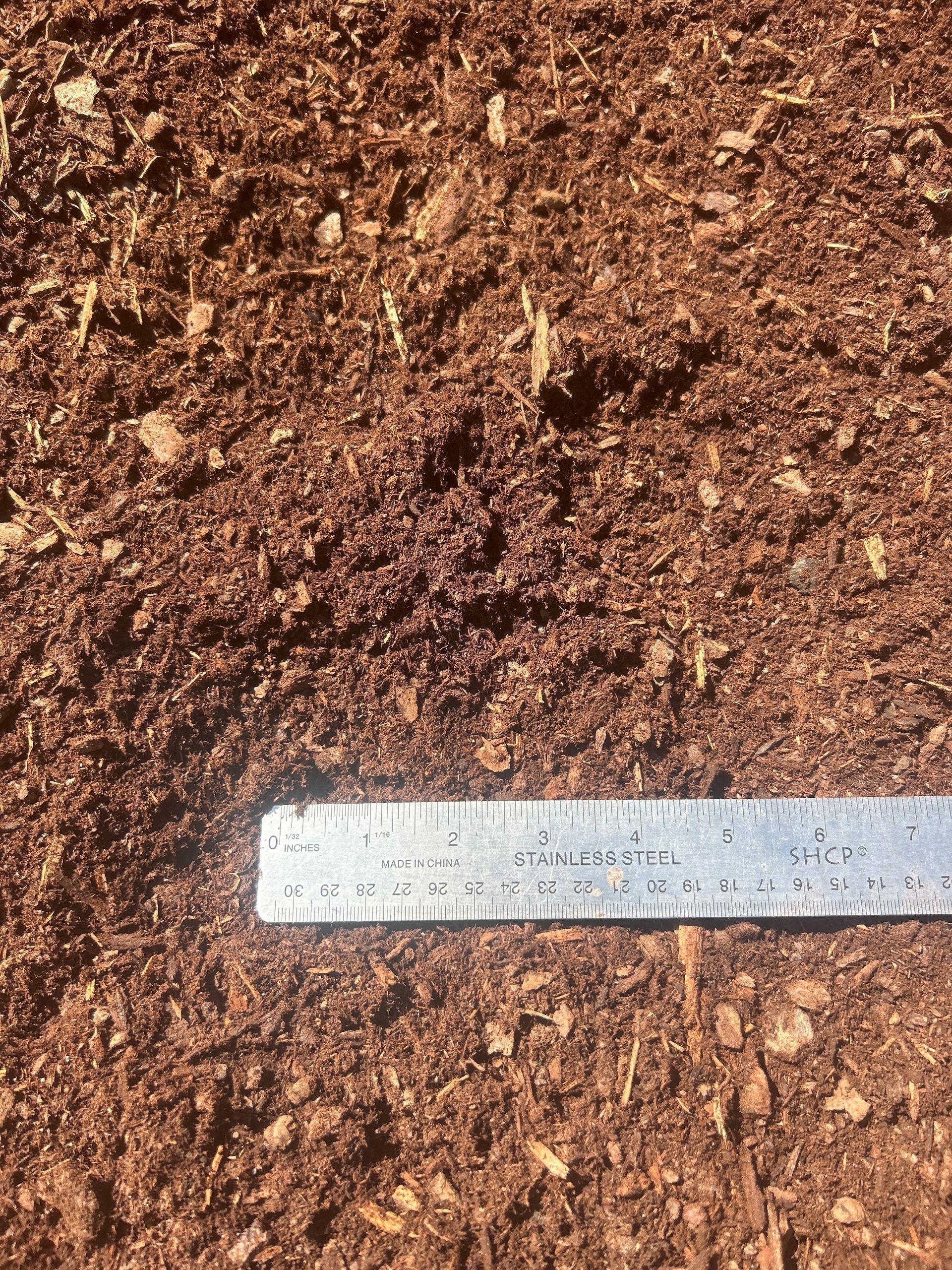 Brown mulch with a metal ruler for scale.
