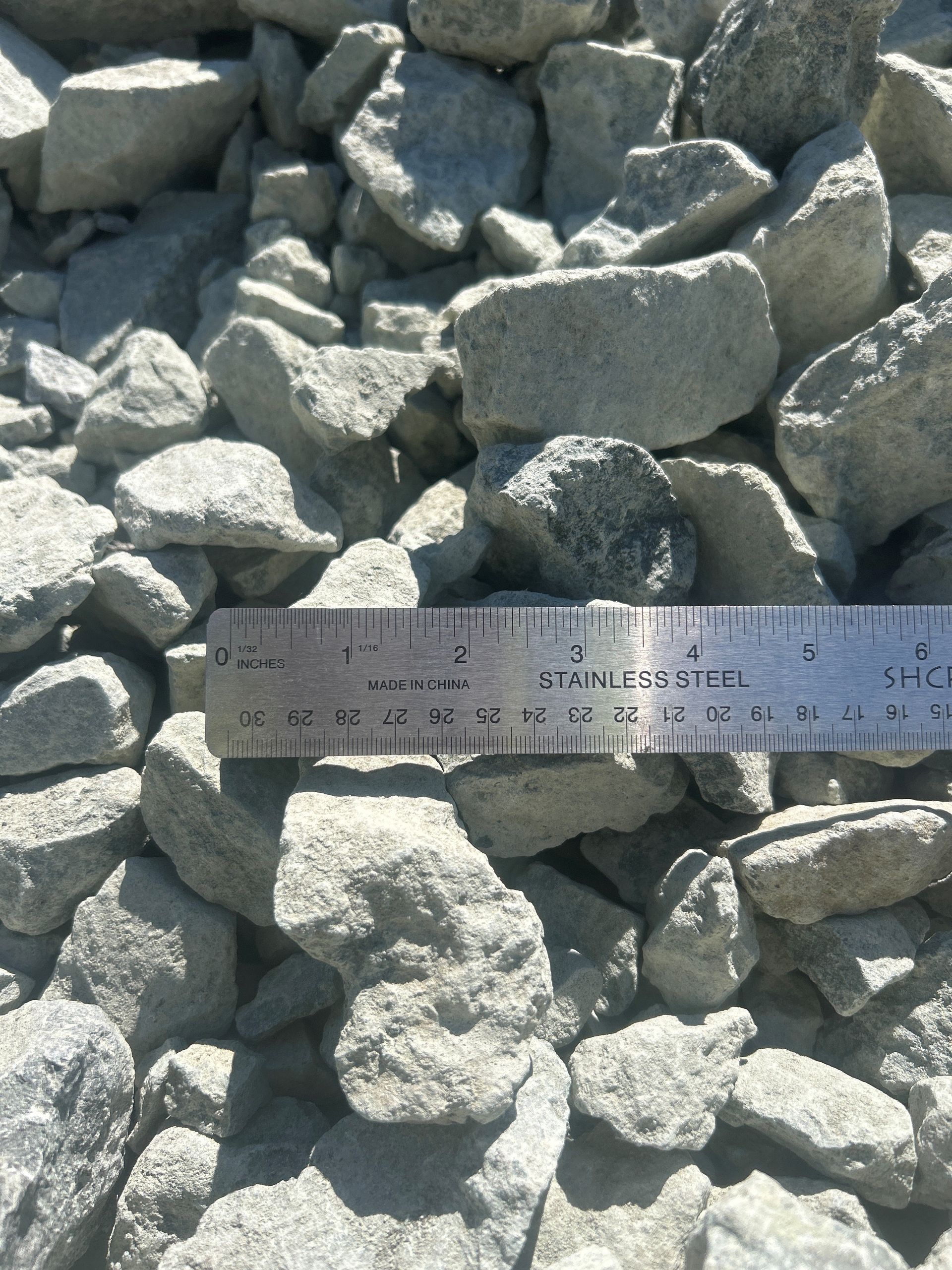 Gray rocks of varying sizes with a ruler for scale.