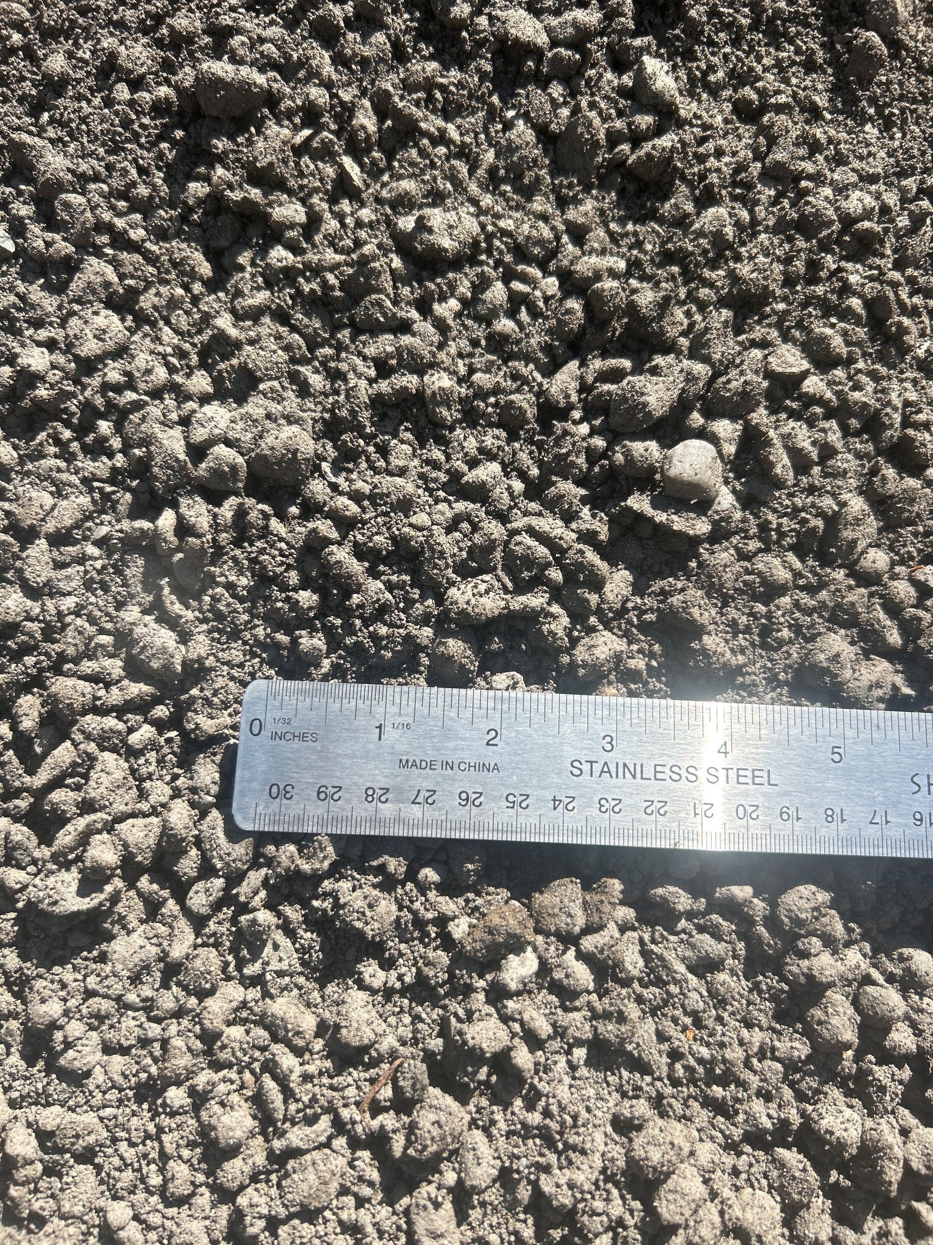 Gray gravel and small rocks with a metal ruler for scale.