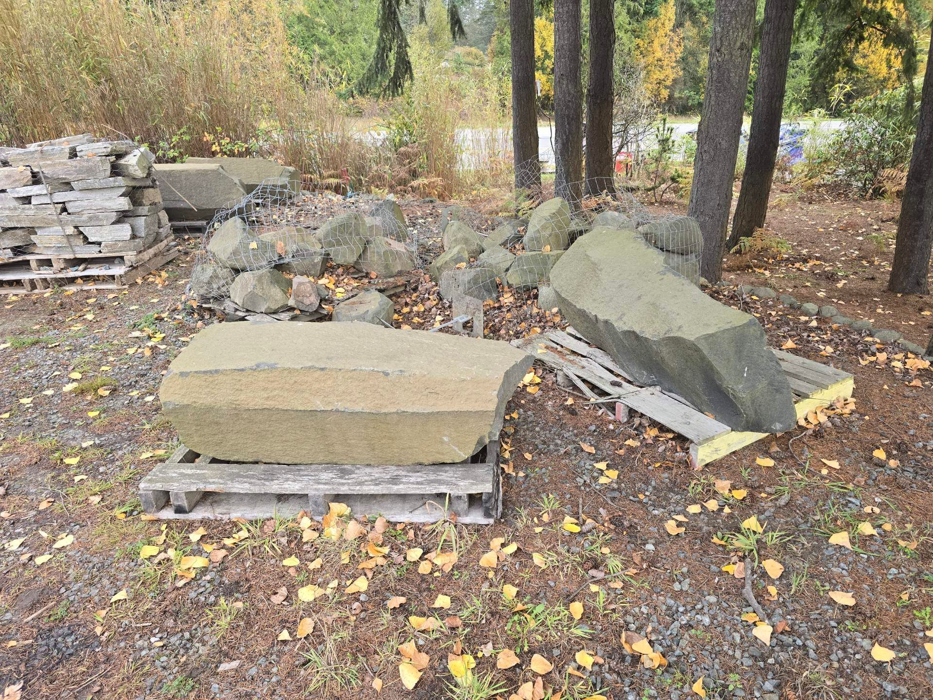 Large, rectangular stone block outdoors, sitting on a base. Trees in the background, sunny day.