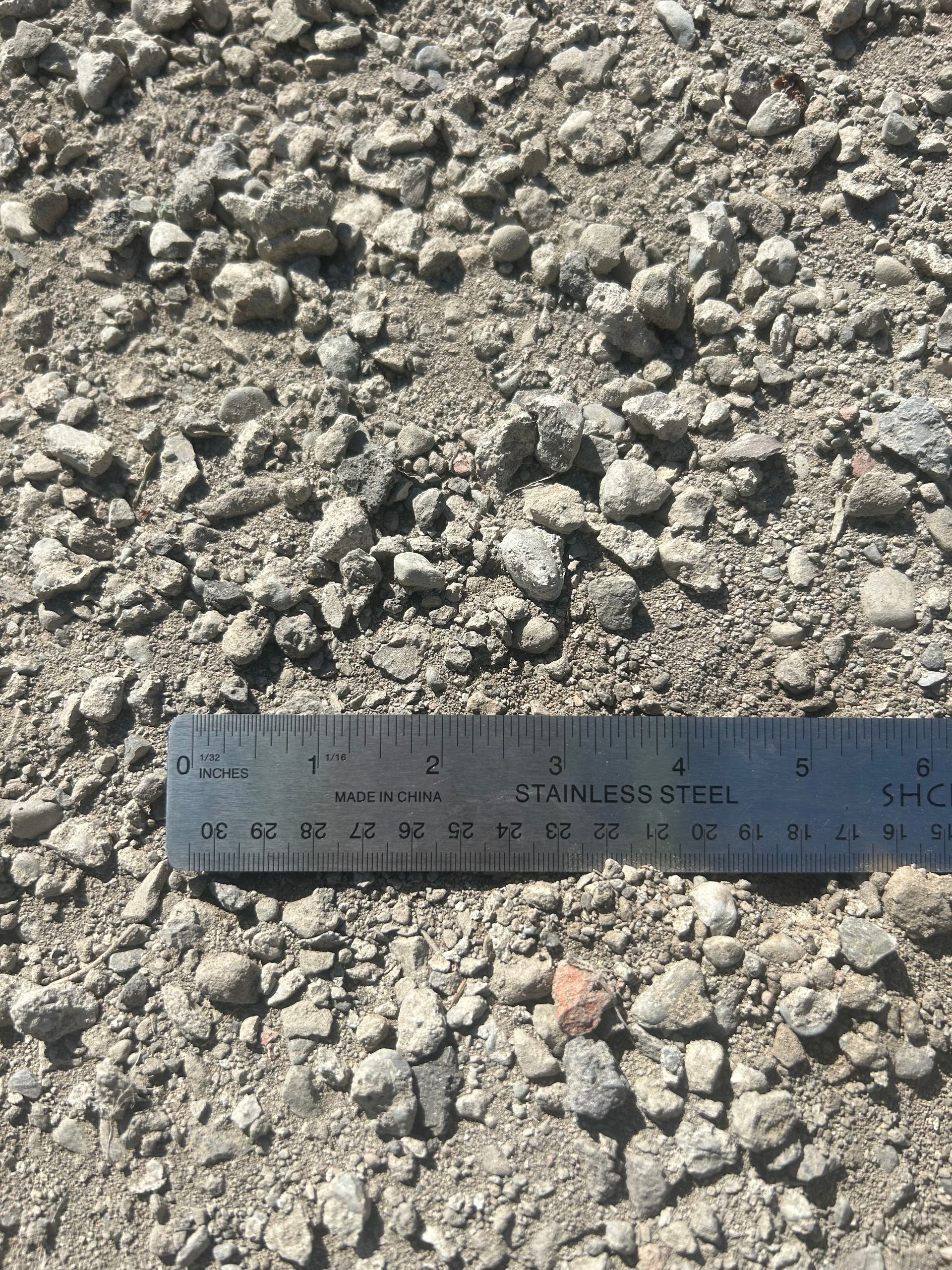 Gravel and small rocks with a ruler for scale. The rocks are gray and beige.