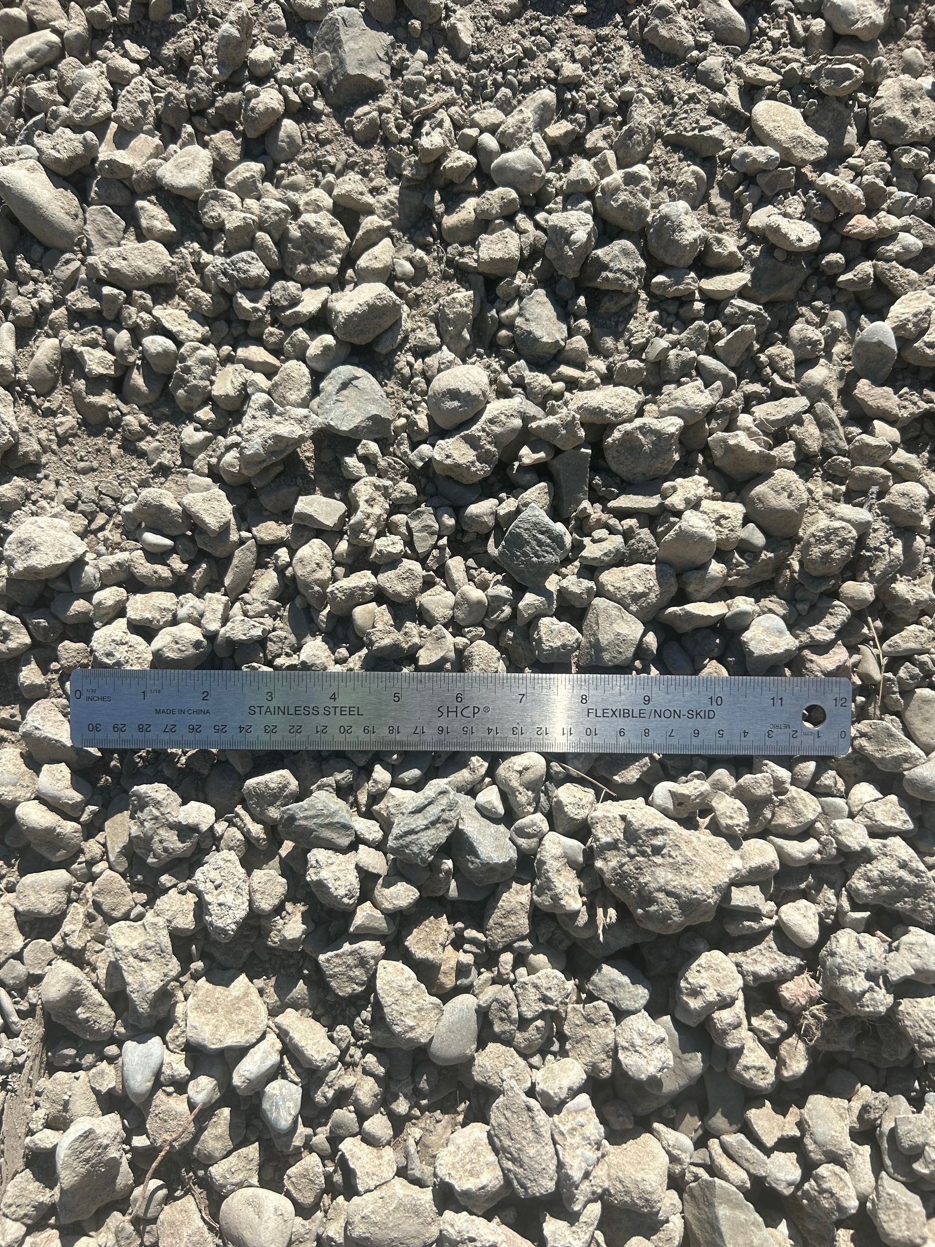 Gravel pile with a ruler for scale; mostly gray and tan stones.