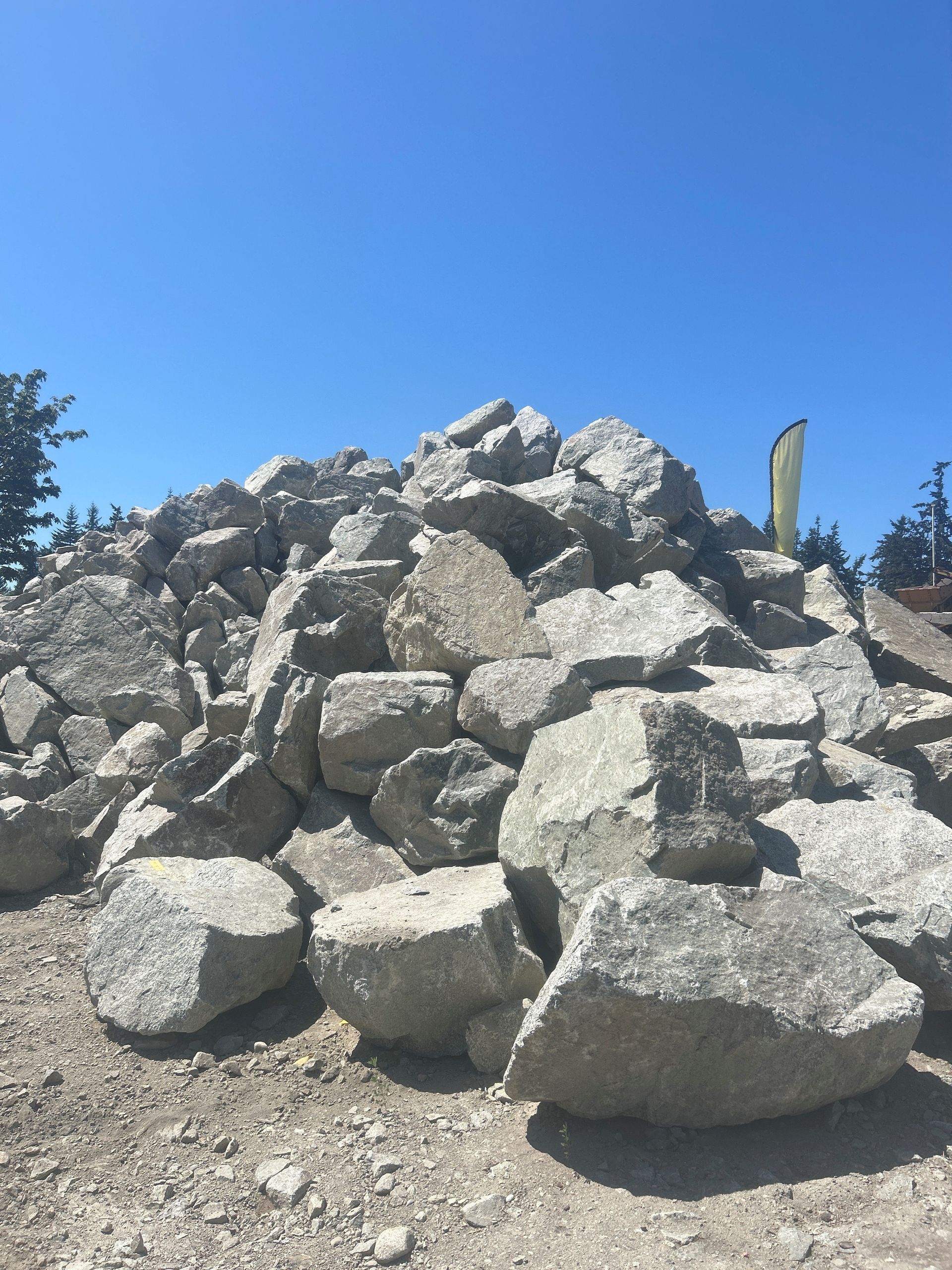 Pile of large, gray, rough-cut stones under a bright blue sky.