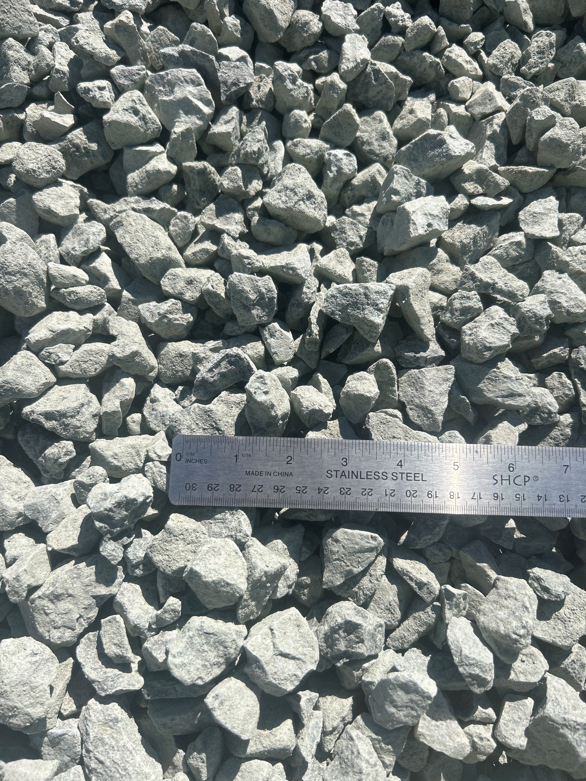 Gray gravel with a ruler laid across it, showing size comparison.