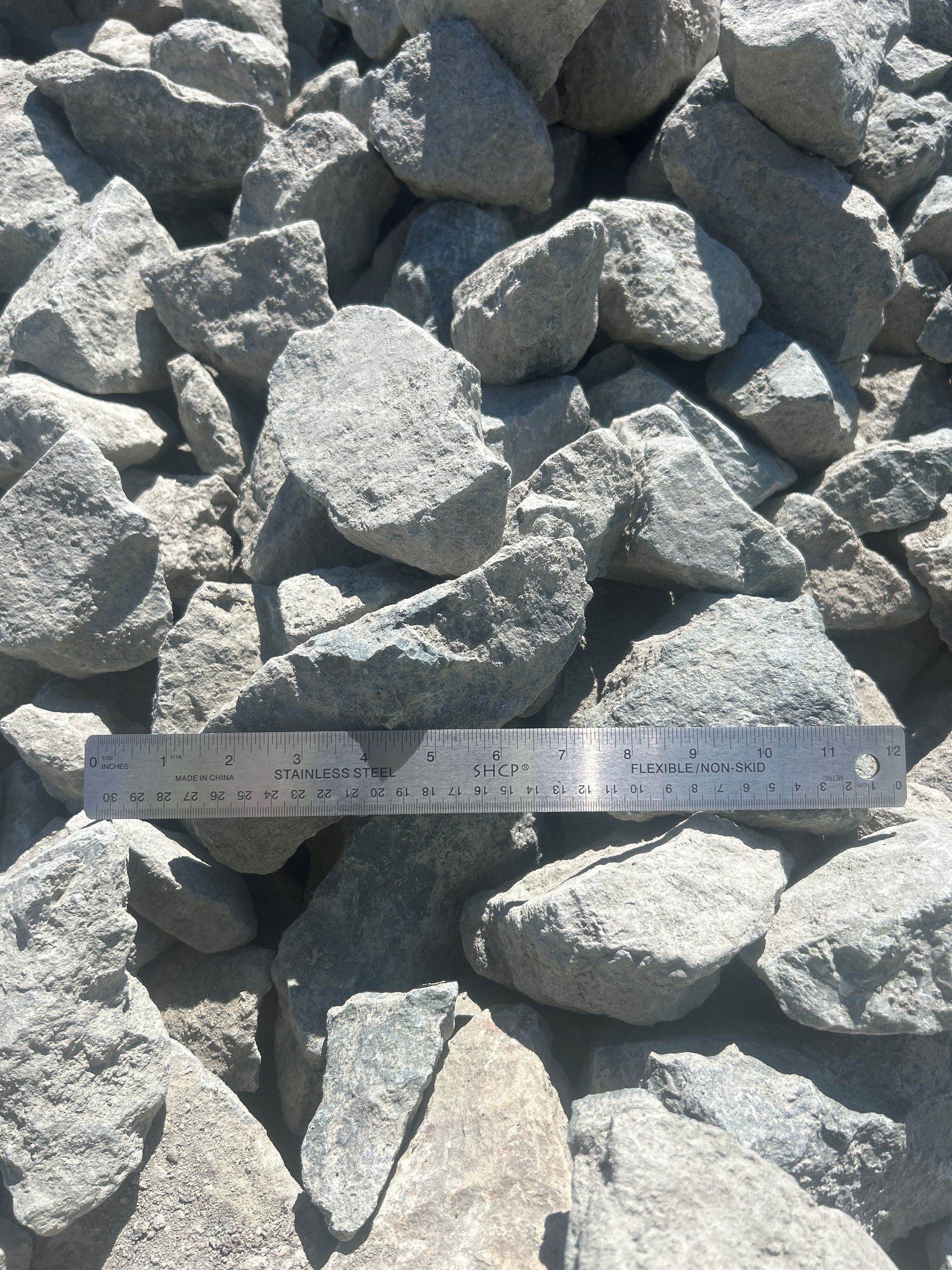 Pile of gray rocks with a ruler for scale.