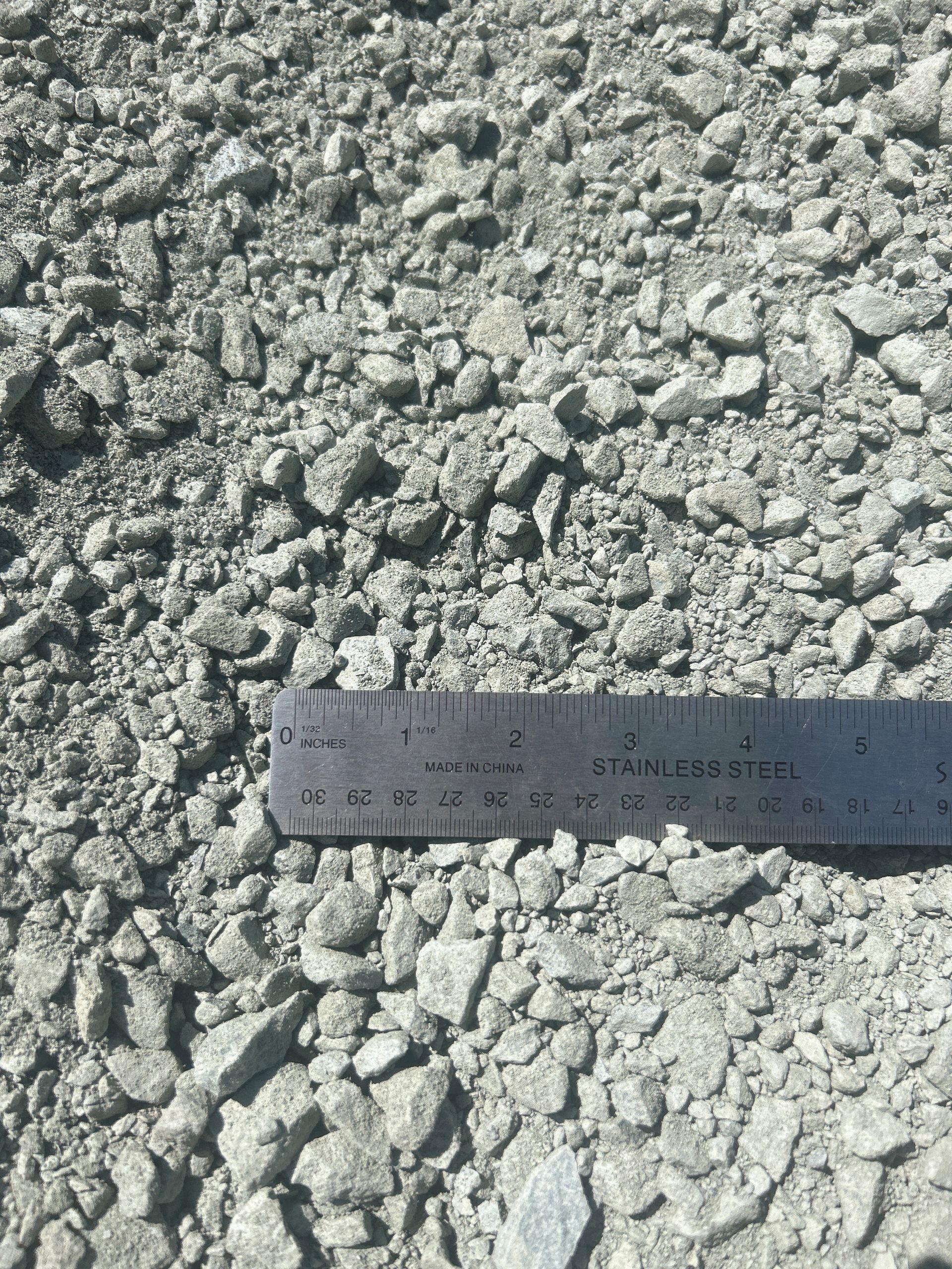 Gray gravel with a metal ruler for scale.