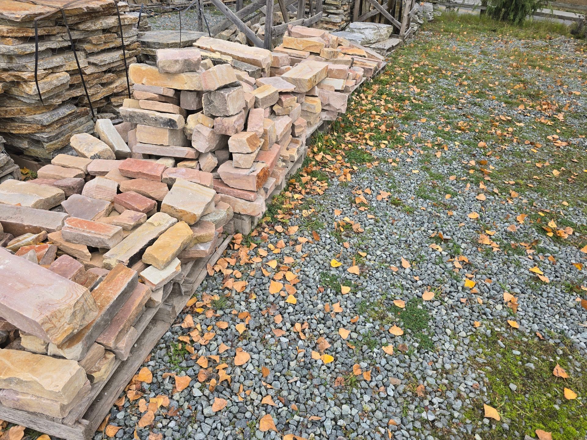 Pile of rectangular, tan-colored stones, some with rough edges, near a metal ruler.