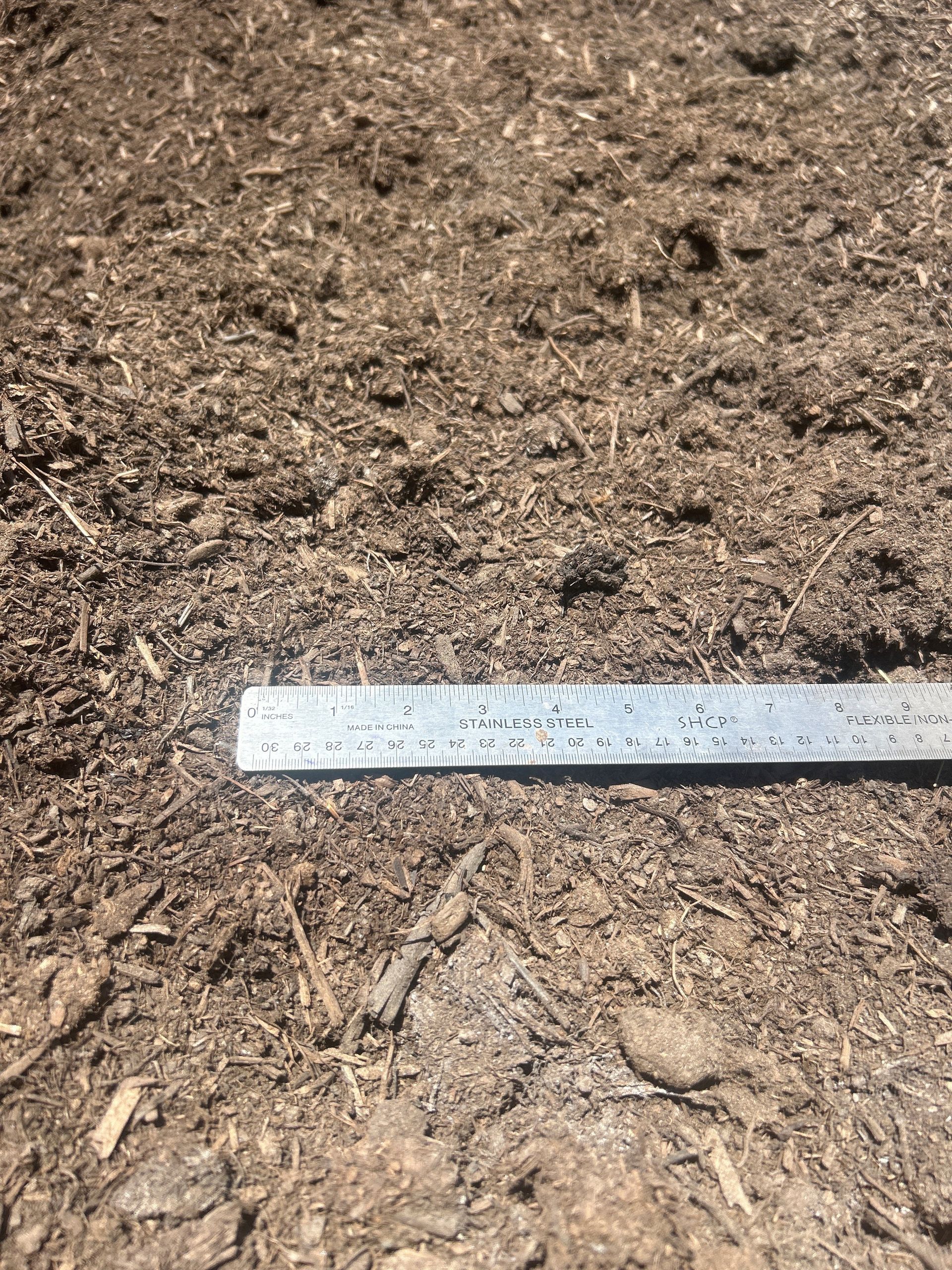 Mulch with a metal ruler laid across it for scale.