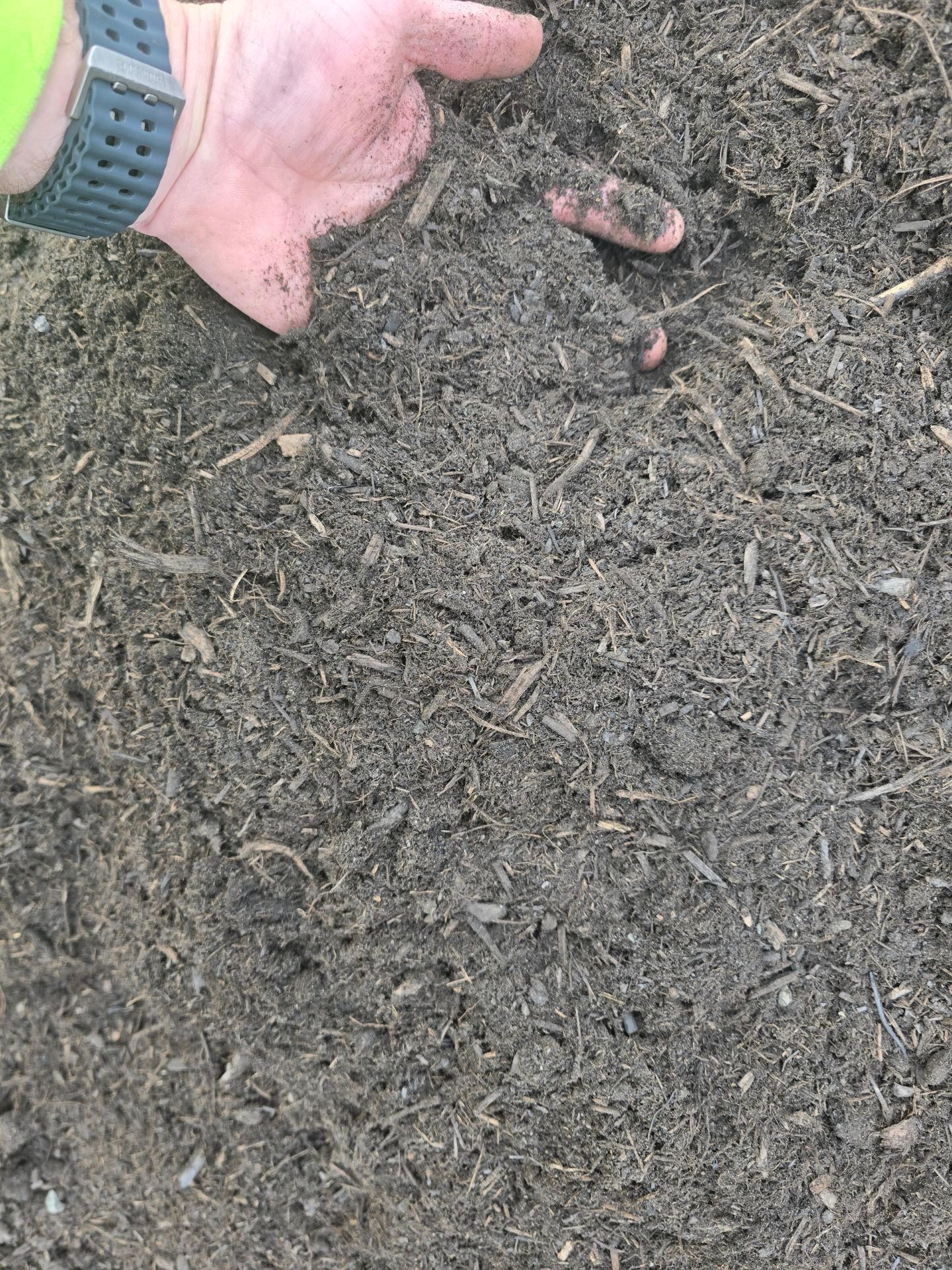 Brown soil and mulch texture with a metal ruler, outdoors.