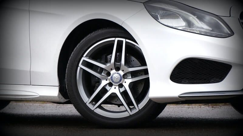 A close up of a white car 's wheel and tire