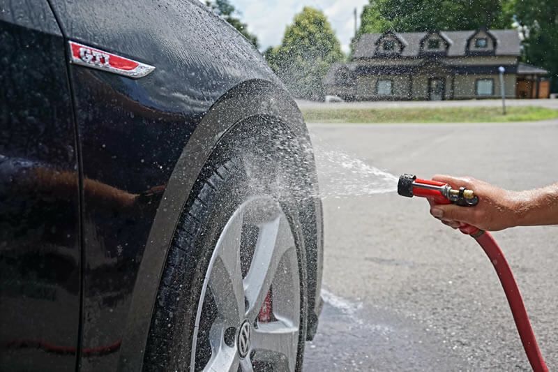 A person is washing a car with a hose.