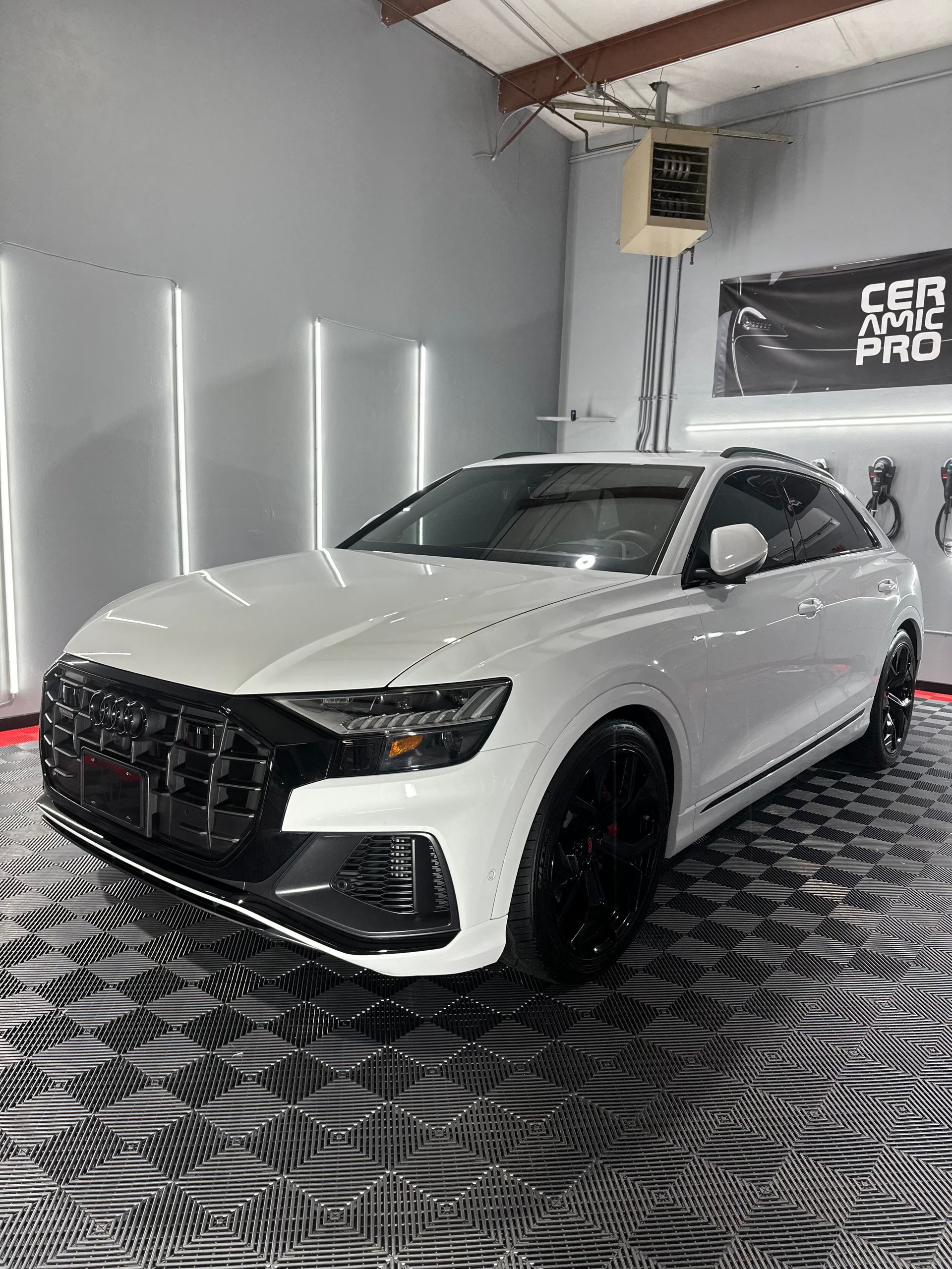 A white audi q8 is parked in a garage.
