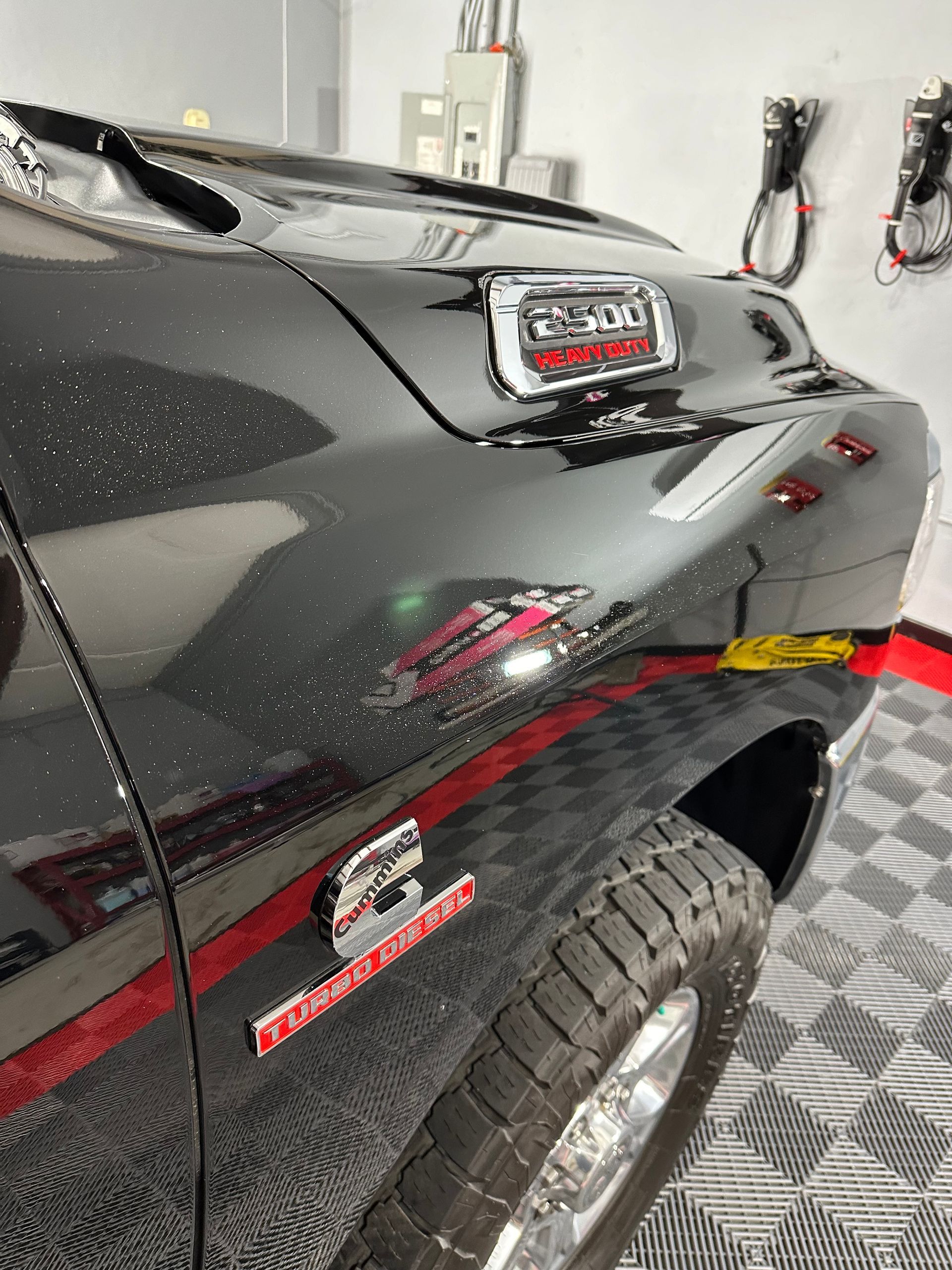 A black truck is parked in a garage on a checkered floor.