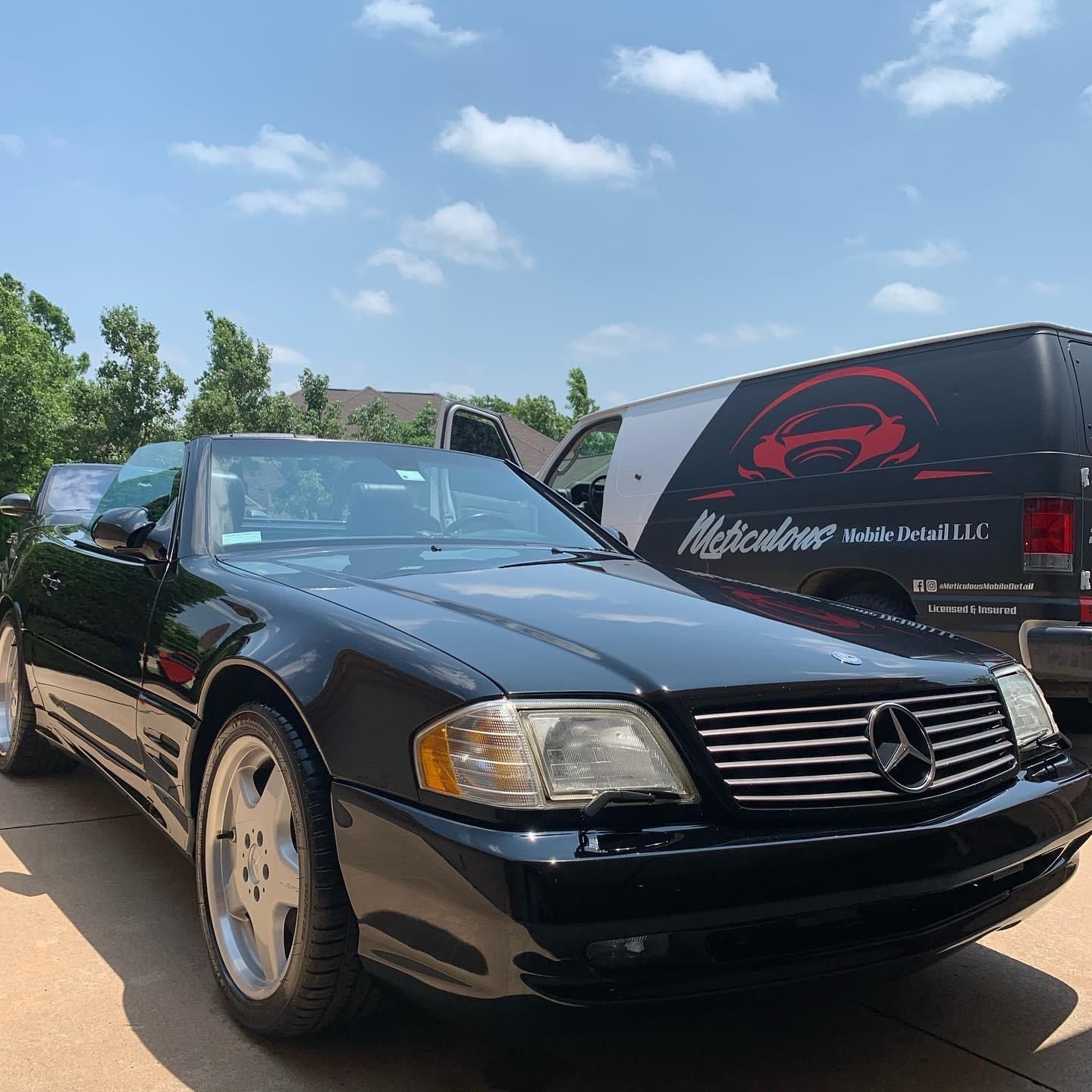 A black car is parked next to a black van.