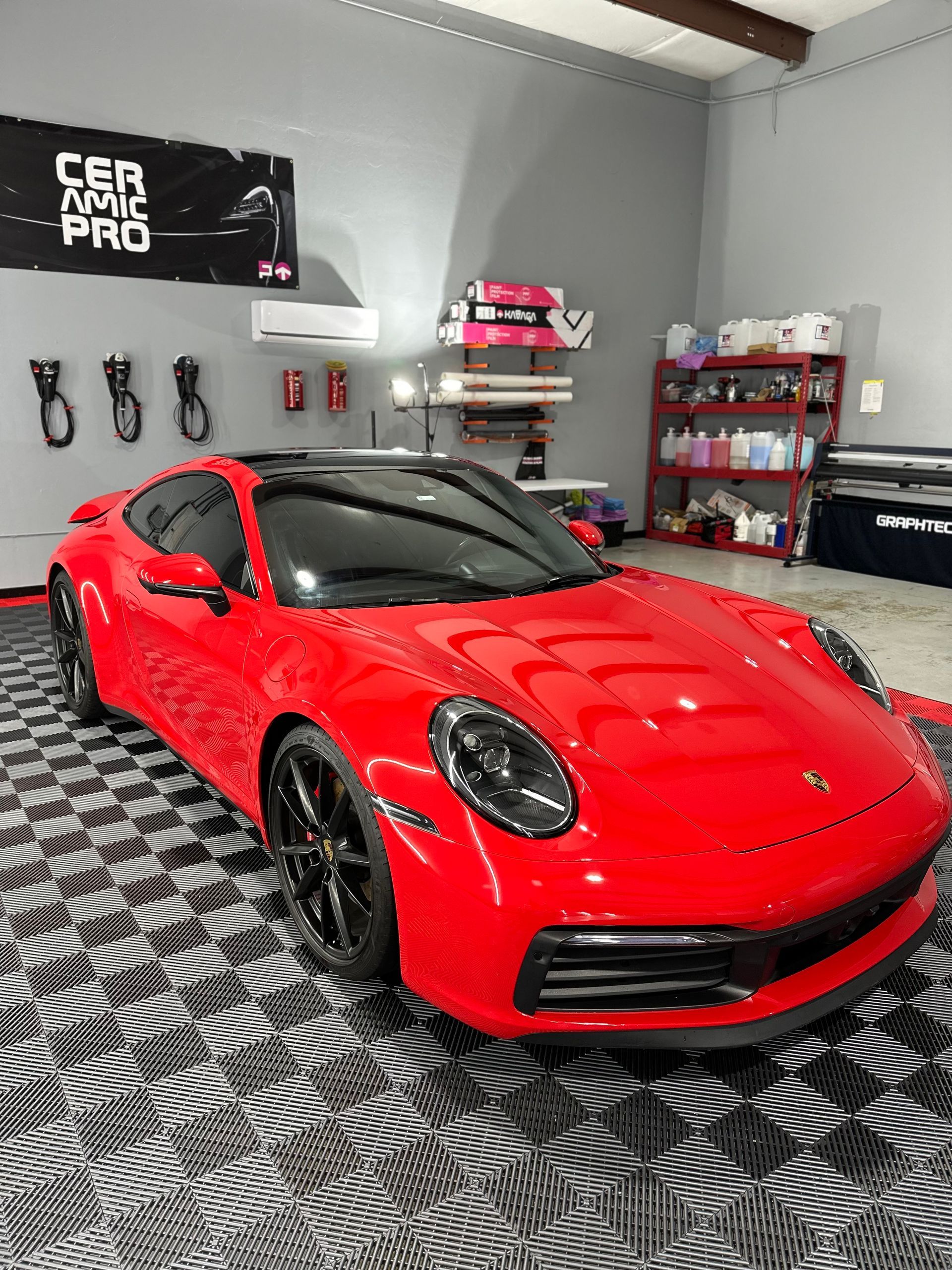 A red porsche 911 is parked in a garage.