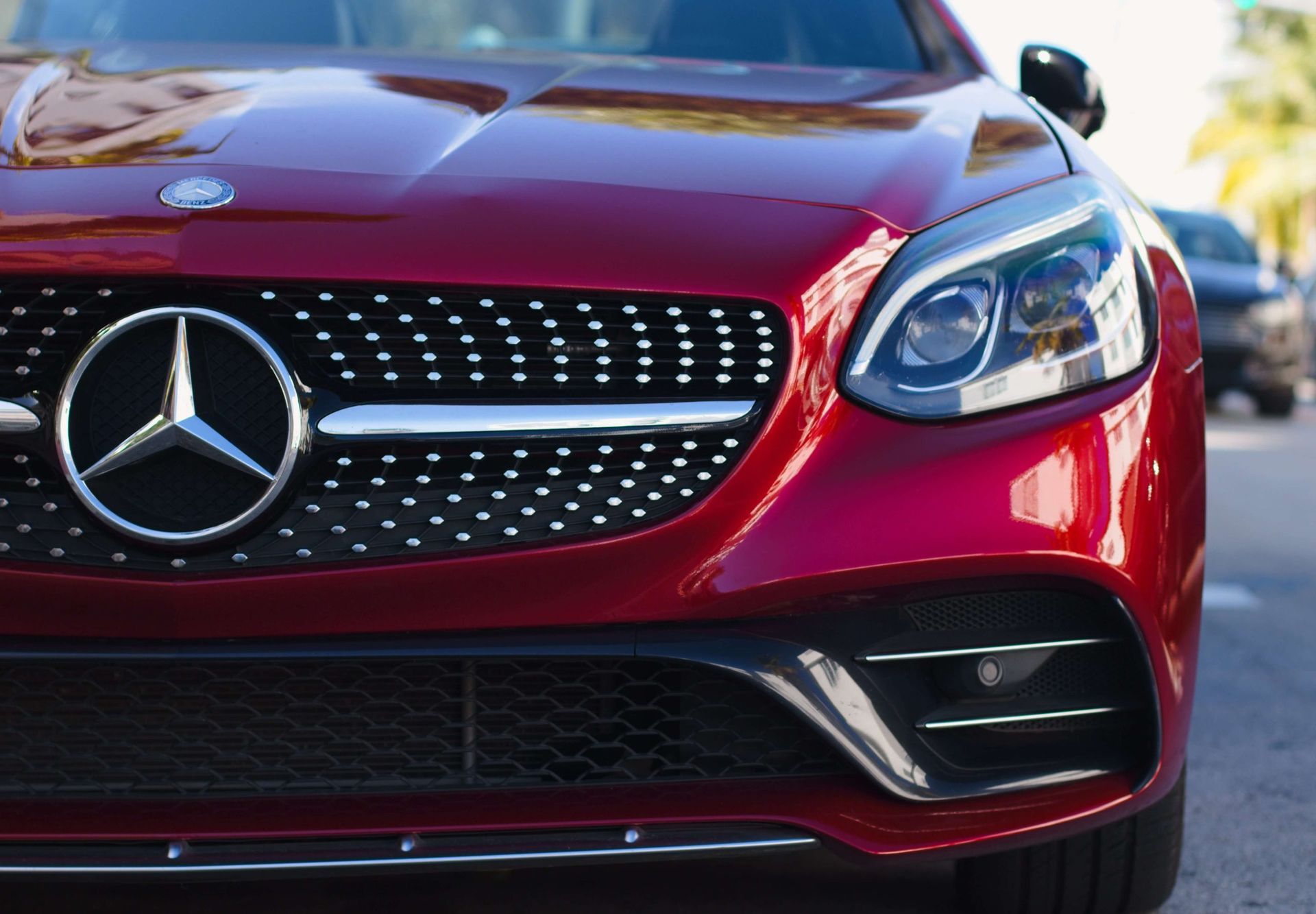 A red mercedes benz is parked on the side of the road