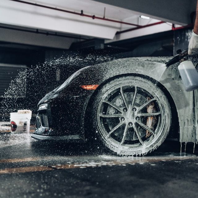 A black sports car is being soaped in a garage