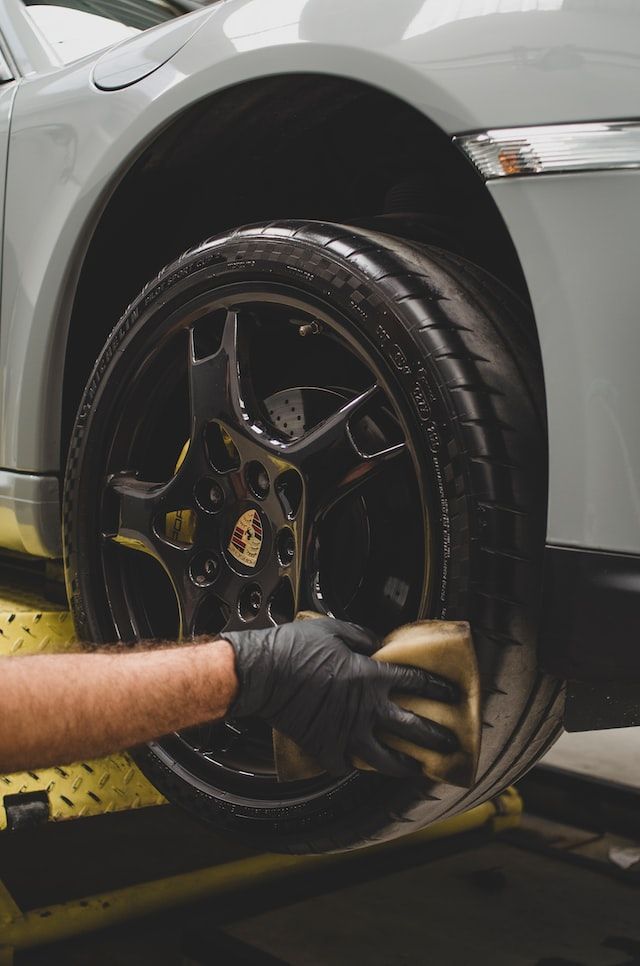 A person is cleaning a car wheel with a sponge.