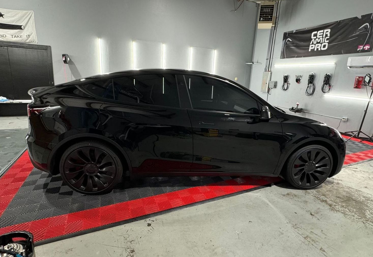 A black tesla model y is parked in a garage.