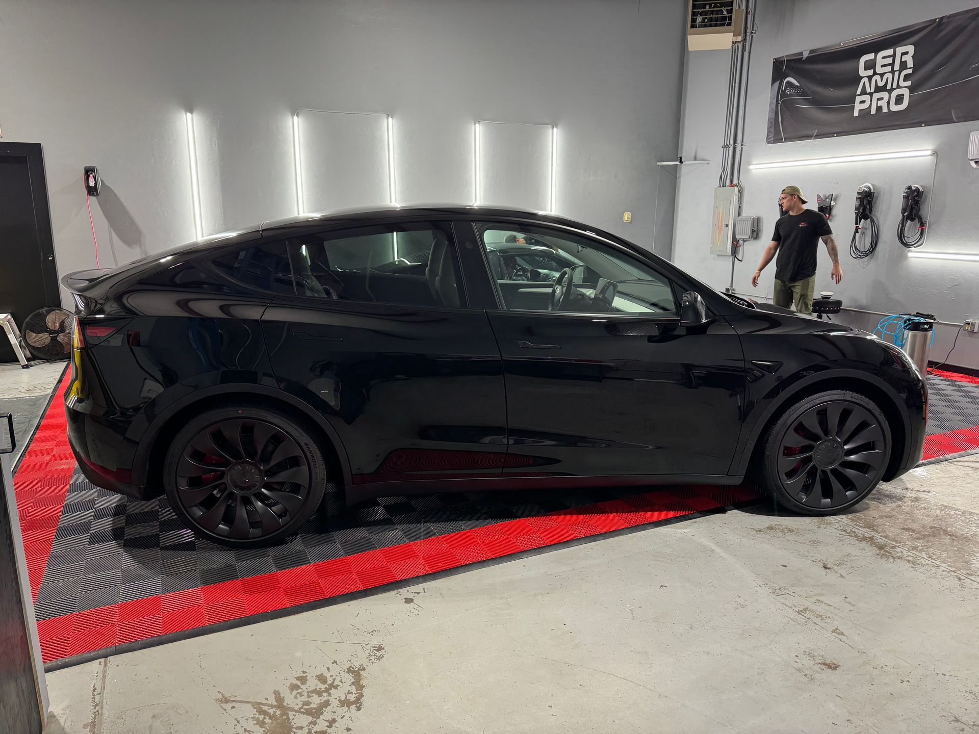 A black tesla model y is parked in a garage.