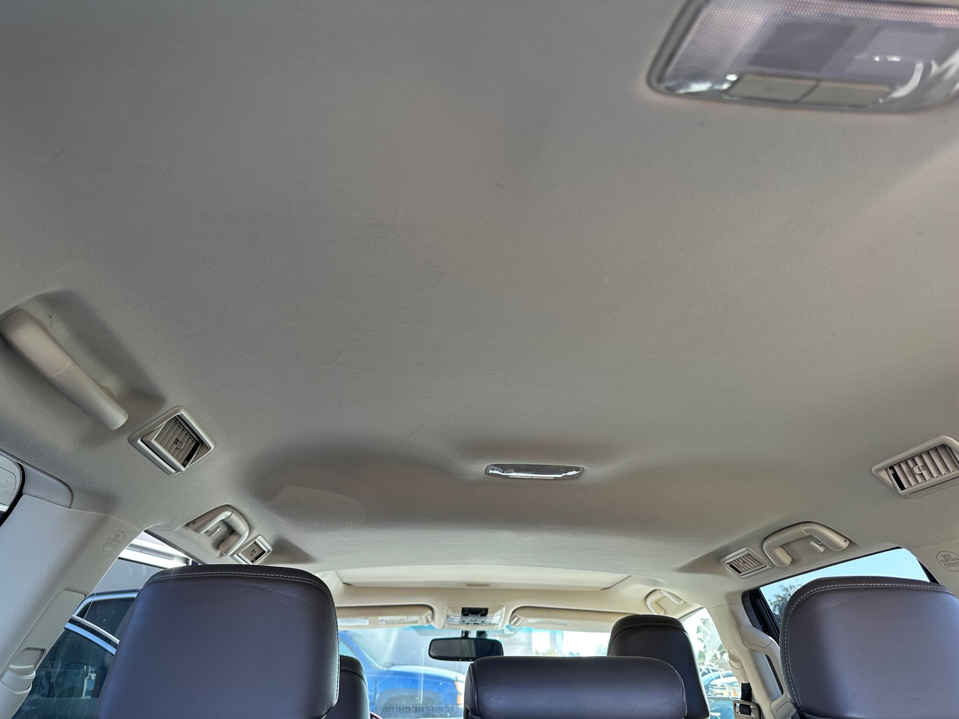 Looking up at the ceiling of a car with black seats.