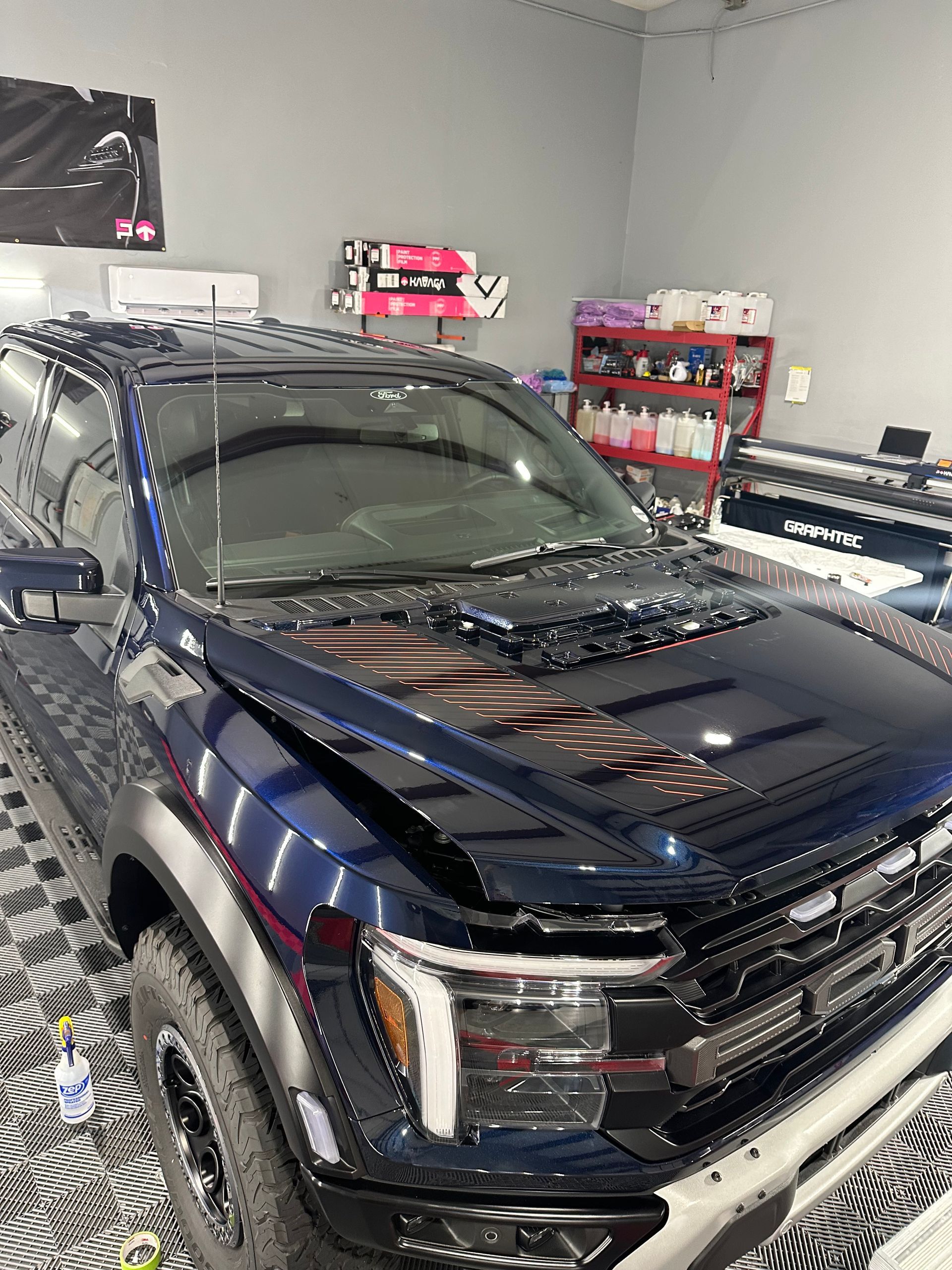 A blue ford f150 raptor is parked in a garage.