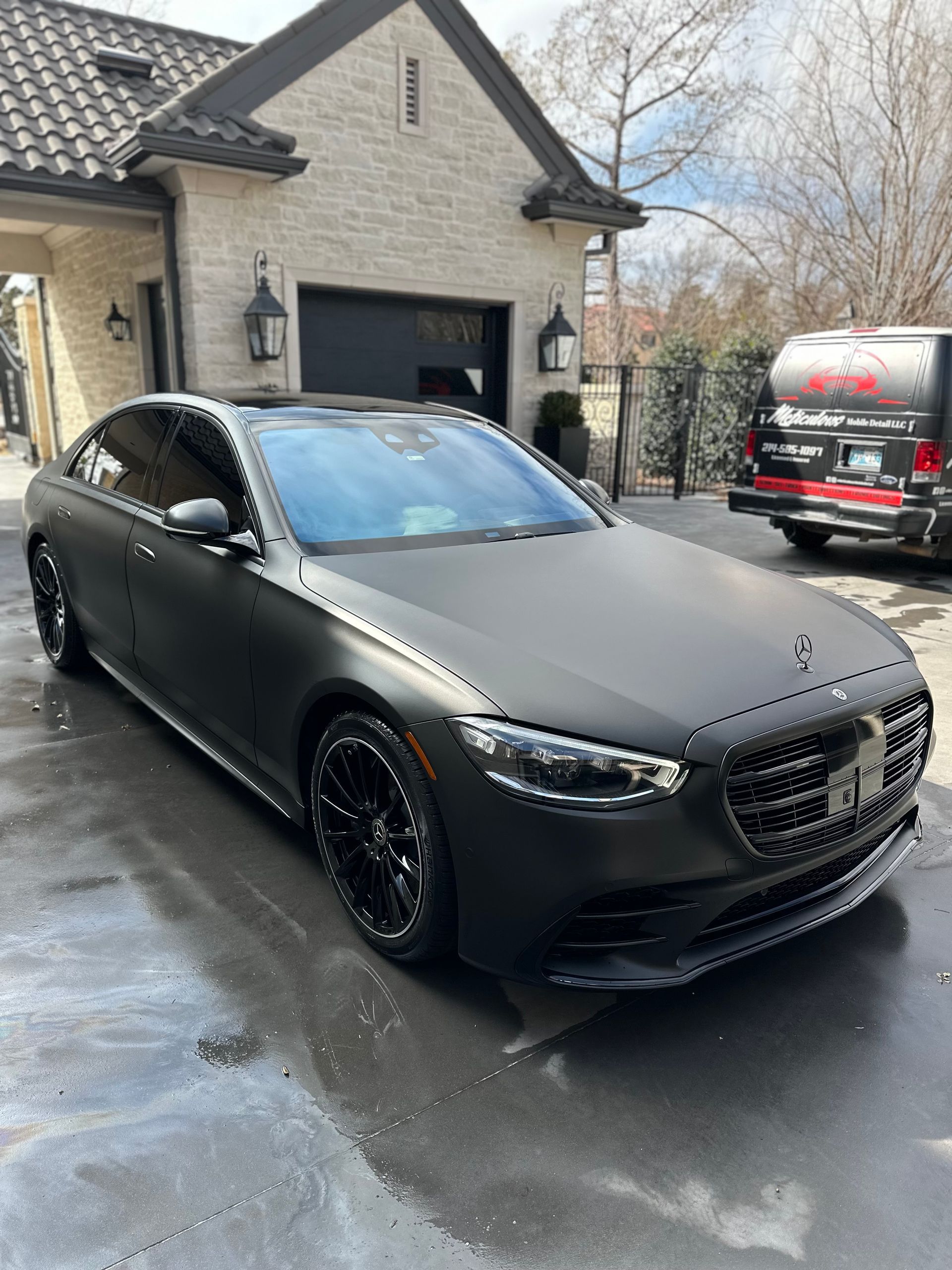 A black mercedes benz s class is parked in front of a house.