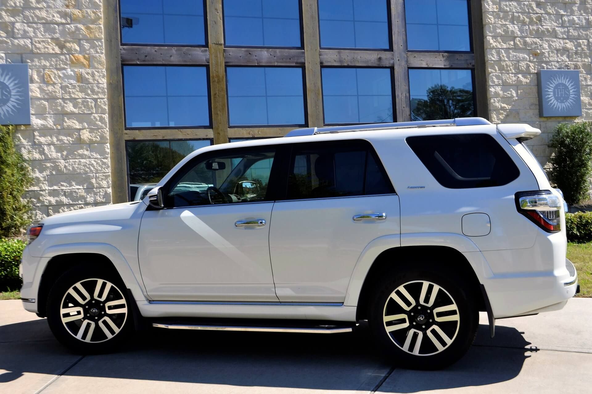 A white suv is parked in front of a building.