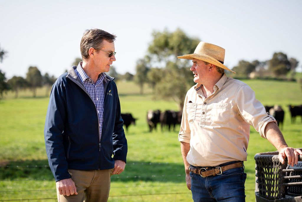 Two men are standing in a field talking to each other.